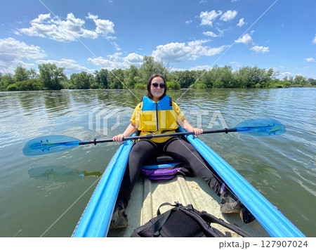 Woman Kayaking on a Calm River. Peaceful Outdoor Adventure. Woman Kayaking on a Calm River. Peaceful Outdoor Adventure. 127907024