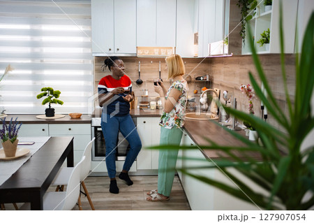 Two friends enjoy a cozy chat in a modern kitchen Two friends enjoy a cozy chat in a modern kitchen 127907054