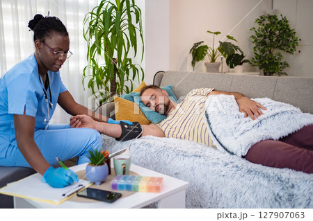 Caring healthcare provider assists patient at home today 127907063