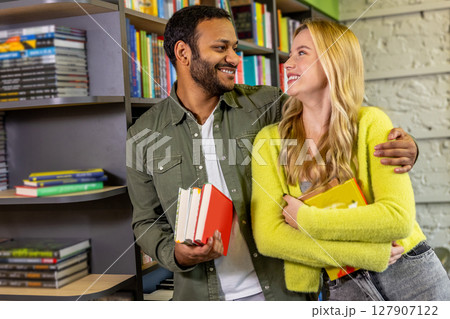 Smiling contented couple at the library reading books Smiling contented couple at the library reading books 127907122