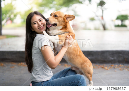 Caring Embrace with Corgi. Woman hugging her dog in a serene outdoor setting. 127908687