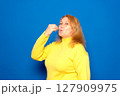 Caucasian woman in her 40s wearing a yellow sweater with a positive and happy smile showing a delicious perfect gourmet sign isolated over blue colored background 127909975