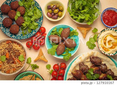 Middle eastern or Arab dishes and assorted meze on light beige background. Meat kebab, falafel, hummus, sambusak, rice, kibbeh, pita. Halal food. Lebanese cuisine 127910167