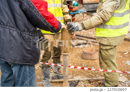 Man cutting and cleaning soil sample for laboratory analysis. Preparation of core material for geotechnical testing and scientific evaluatio 127910607