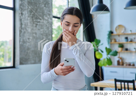 Young sad stressed woman standing at home using smartphone 127910721