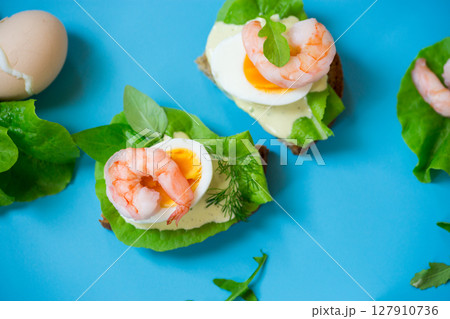 Sandwich with egg and shrimp on blue background from above 127910736