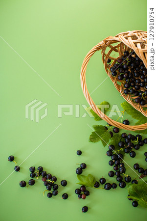 Ripe juicy blackcurrant berries on a green background 127910754