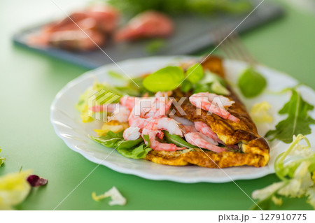 Serving omelette with shrimps on a green background 127910775
