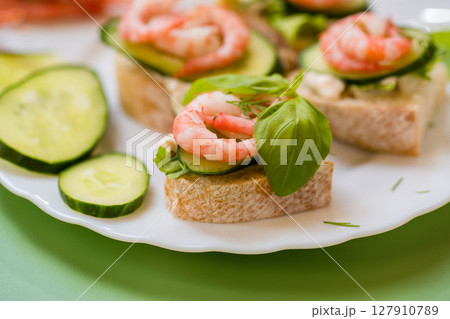 Minimalistic canapes with shrimps, lettuce and cucumber on a green background Minimalistic canapes with shrimps, lettuce and cucumber on a green background 127910789