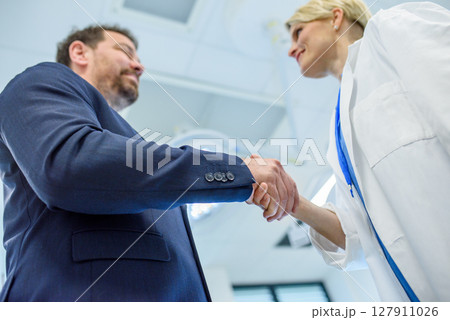 Doctor and pharmaceutical sales representative finalizing deal and partnership in hospital setting. 127911026