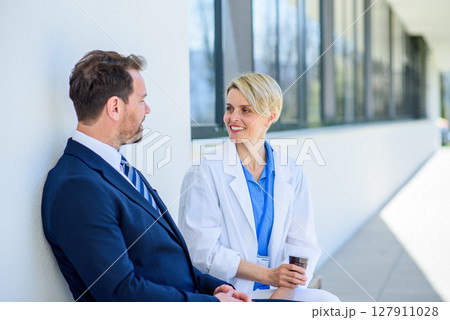 Doctor and pharmaceutical representative talking about new drug, in front of hospital. 127911028