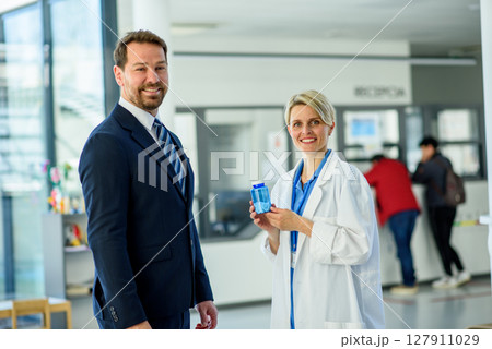 Doctor and pharmaceutical representative talking about new drug, clinical setting. 127911029
