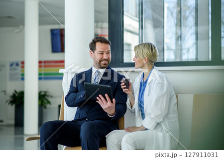 Pharmaceutical sales representative introducing new medication to female doctor. 127911031