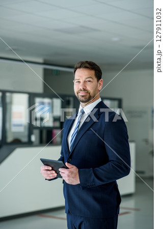 Business professional standing with tablet in hand, ready for presentation 127911032