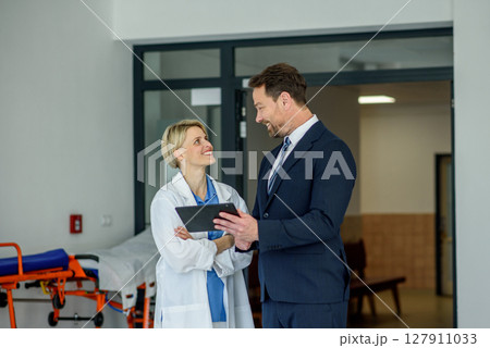 Pharmaceutical sales representative introducing new medication to female doctor. 127911033