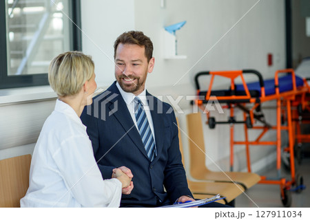 Doctor meeting pharmaceutical representative and shaking his hand, clinical setting. 127911034