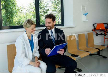 Doctor and pharmaceutical representative talking about new drug, clinical setting. 127911035