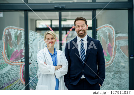 Male hospital manager standing next to female doctor, medical setting. Male hospital manager standing next to female doctor, medical setting. 127911037