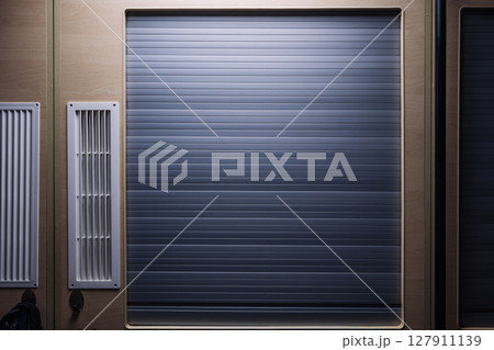 Closed rolling shutter door and ventilation grilles in a modern interior design 127911139