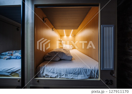 Capsule hotel room number twenty-three featuring comfortable bed, blanket and pillow 127911170