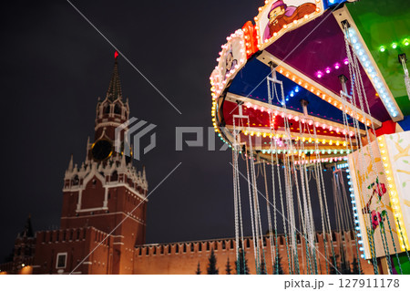 Colorful illuminated carousel spinning in front of the Moscow Kremlin at night 127911178