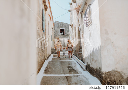 A family with two toddler children walking in town on summer holiday. 127911826