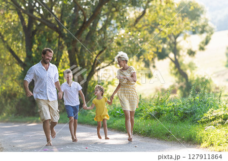 A family with small children running barefoot on a road in summer. A family with small children running barefoot on a road in summer. 127911864