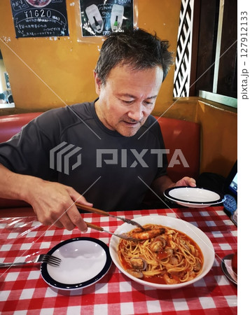 イタリアンレストランで漁師風パスタを食べるシニアの男性 イタリアンレストランで漁師風パスタを食べるシニアの男性 127912133