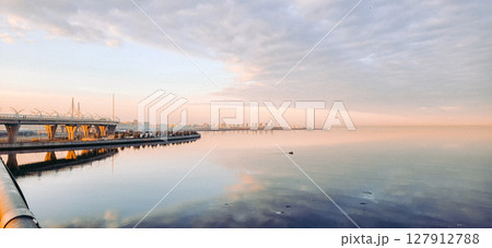 Spring landscape. Panoramic view of beautiful dawn on bay. Cumulus clouds over water in bright light. Boat with fisherman in sea. Rising rays of sun are reflected on coastline. High quality photo Spring landscape. Panoramic view of beautiful dawn on bay. Cumulus clouds over water in bright light. Boat with fisherman in sea. Rising rays of sun are reflected on coastline. High quality photo 127912788