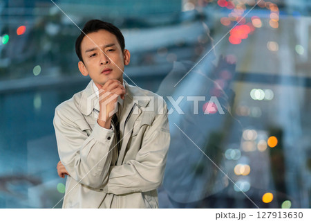 高層ビルをバックに腕組みをして考える作業着の男性 127913630