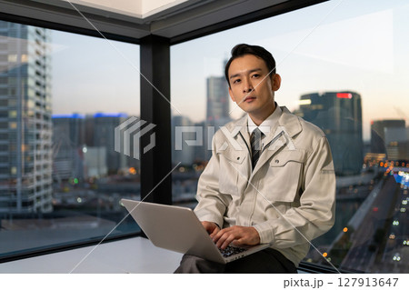 建設現場でパソコンを操作する作業着の男性 127913647