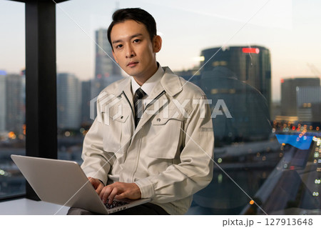 オフィスでパソコンを操作する作業着の男性 127913648