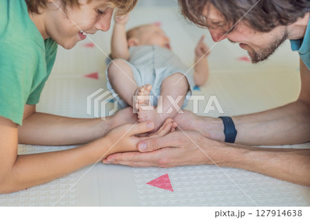 Father, son, and newborn baby lying on the floor in a cozy nursery, celebrating the arrival of their newest family member. Parenthood, bonding, and family love concept Father, son, and newborn baby lying on the floor in a cozy nursery, celebrating the arrival of their newest family member. Parenthood, bonding, and family love concept 127914638