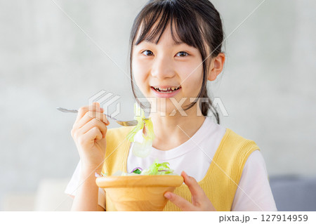 リビングでサラダを食べる女の子 127914959