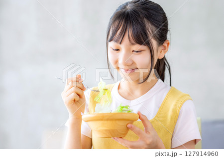 リビングでサラダを食べる女の子 127914960