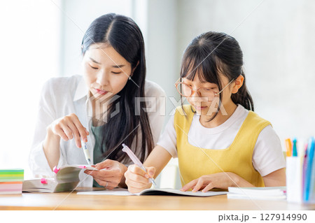 勉強をする小学生と教えるママ 127914990