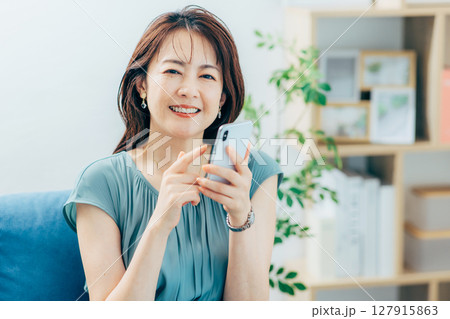リビングでスマホを見るミドルの女性 リビングでスマホを見るミドルの女性 127915863