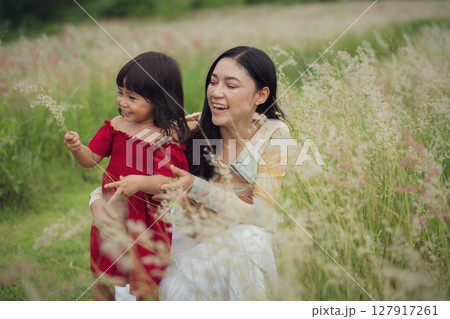 happy mother and daughter playing grass flower in field 127917261