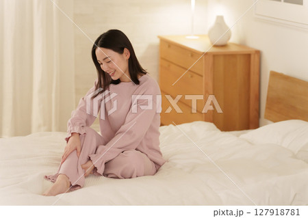 夜ベッドで足のマッサージをする女性 127918781