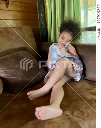 Portrait of a cute little girl sitting on the couch in the living room at home Portrait of a cute little girl sitting on the couch in the living room at home 127919269