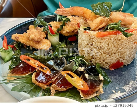 Close up view of delicious fried fish with rice and vegetables on a plate in a restaurant, Seafood stir-fried rice with basil, asian food Close up view of delicious fried fish with rice and vegetables on a plate in a restaurant, Seafood stir-fried rice with basil, asian food 127919349