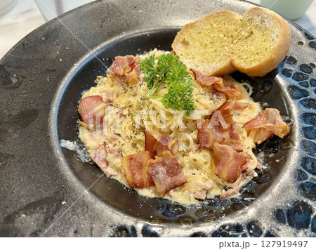 Close up view of delicious Spaghetti Carbonara with bacon and parmesan cheese on black plate 127919497
