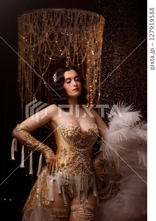 Young woman in vintage corset costume posing under chandelier on dark background 127919588