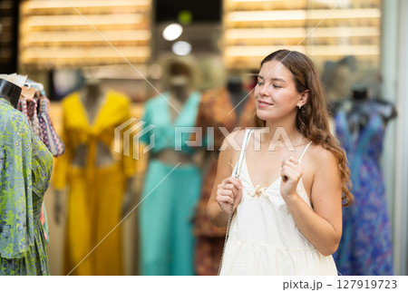 Young girl in white dress is looking for something at street market - looking at goods with interest Young girl in white dress is looking for something at street market - looking at goods with interest 127919723