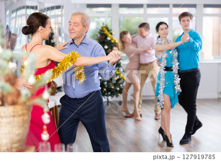 Senior man dancing elegant waltz with female colleague at Christmas party 127919785