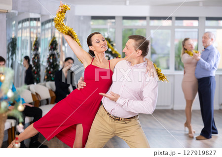 Christmas and New Year holiday - couples dancing with tinsel near Christmas tree Christmas and New Year holiday - couples dancing with tinsel near Christmas tree 127919827