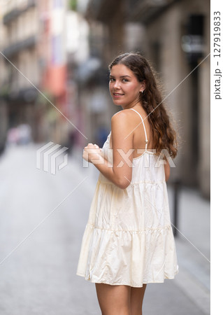 Young woman walks along city street 127919833