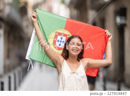 Young woman with Portuguese flag on city street 127919847