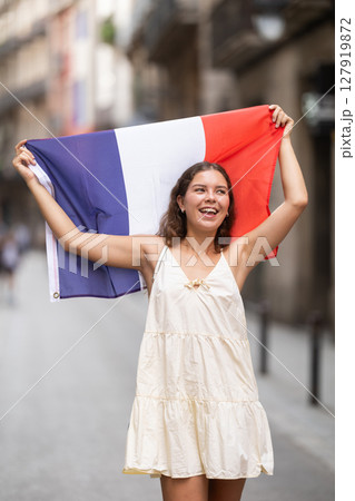 Woman waving France flag on street of summer European city Woman waving France flag on street of summer European city 127919872
