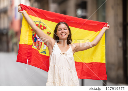Patriotic young woman waving the flag of Spain on city street Patriotic young woman waving the flag of Spain on city street 127919875